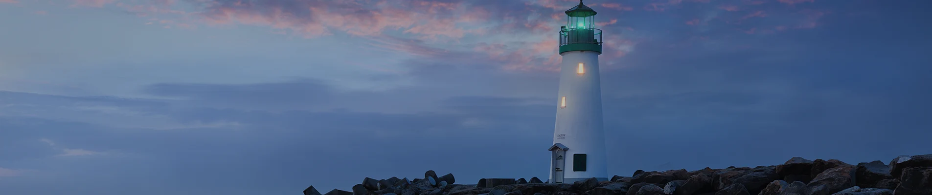 Walton Lighthouse at dusk on a rocky breakwater
