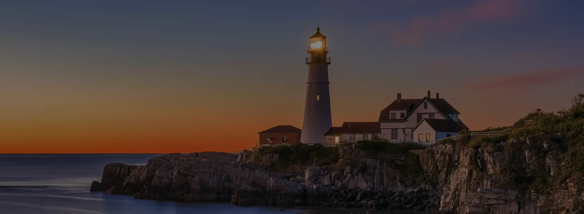 Lighthouse on a rocky coastline at sunset